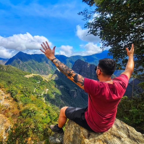 Tourist sitting at the Sun Gate Machu Picchu | Ultimate Trekking