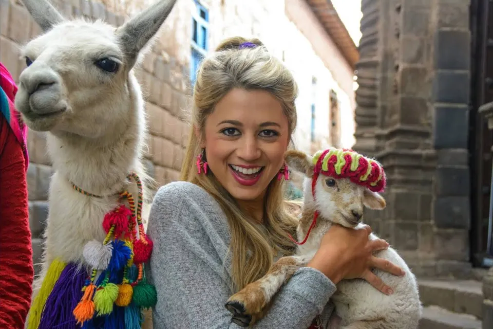 Tourist taking photos with llamas in Cusco | Ultimate Trekking