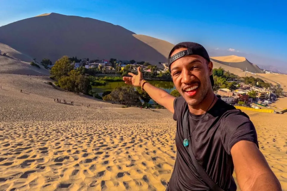 Tourist taking photos from the dunes of Huacachina | Ultimate Trekking