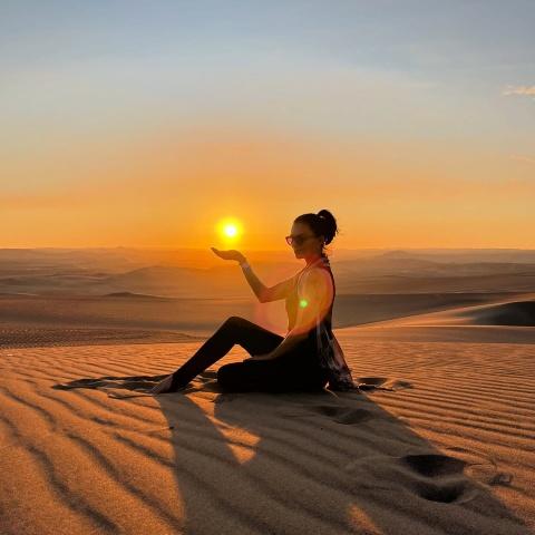 Girl taking a picture at sunset in the Huacachina dunes | Ultimate Trekking